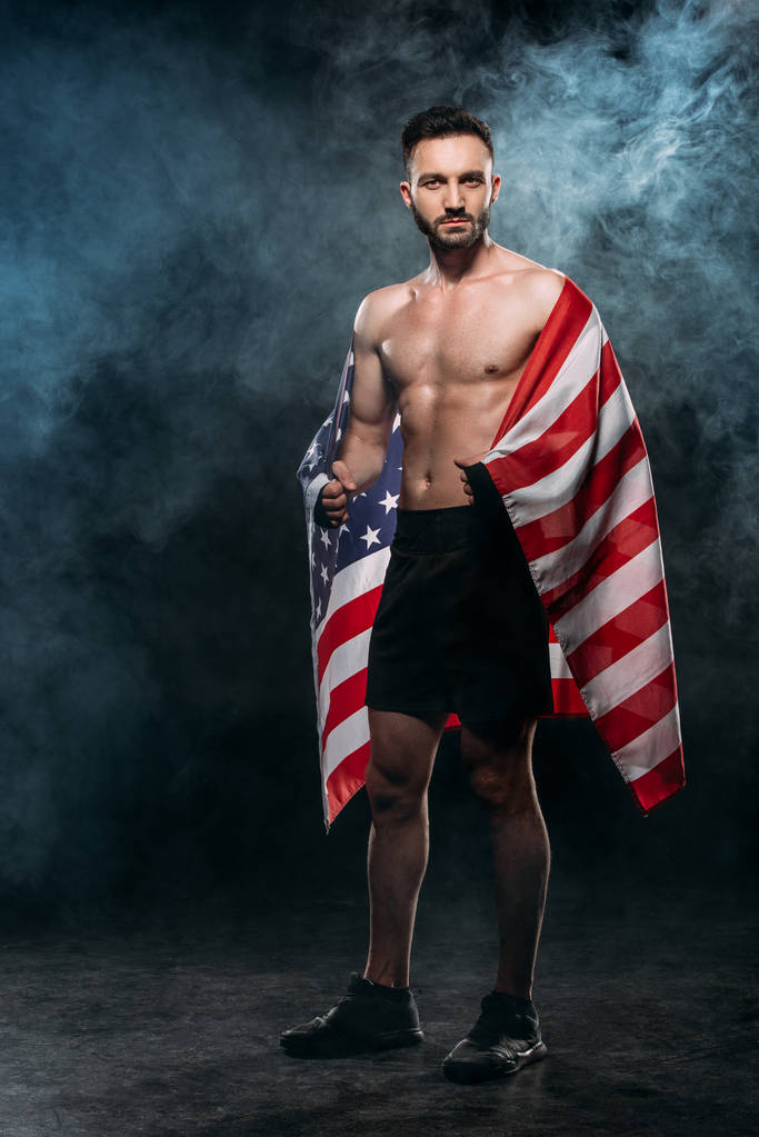 handsome man holding american flag on black with smoke - Photo, Image