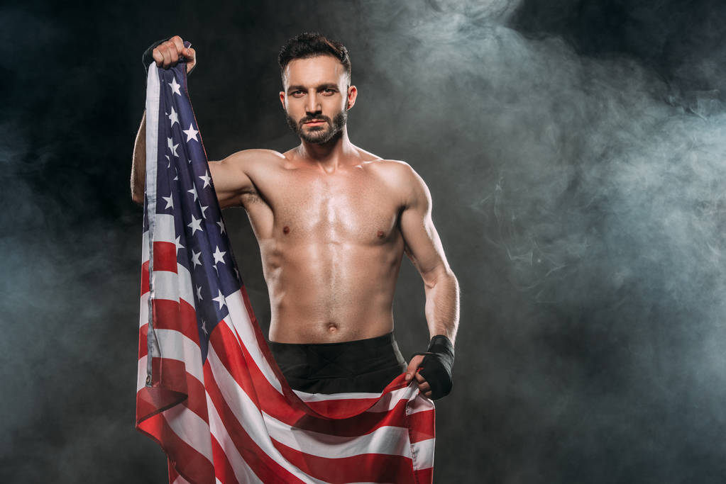 shortless αθλητής κρατώντας αμερικανική σημαία σε μαύρο με καπνό - Φωτογραφία, εικόνα
