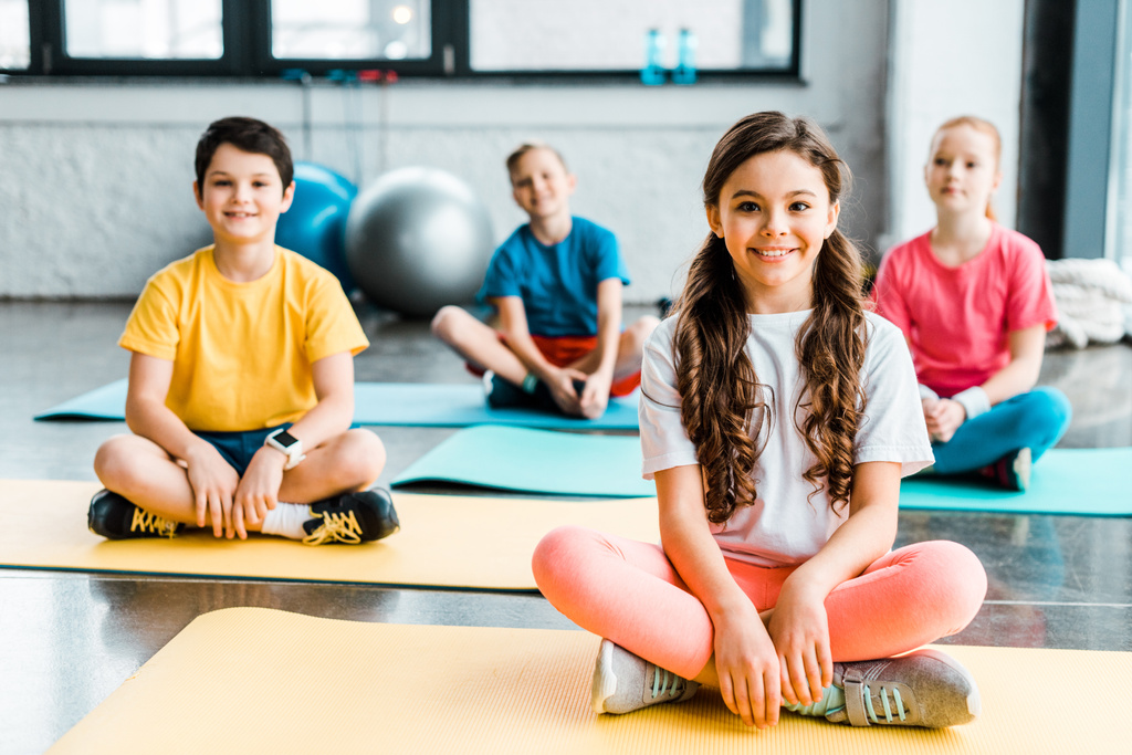 Enfants excités s'étirant sur des tapis de fitness dans la salle de gym
 - Photo, image
