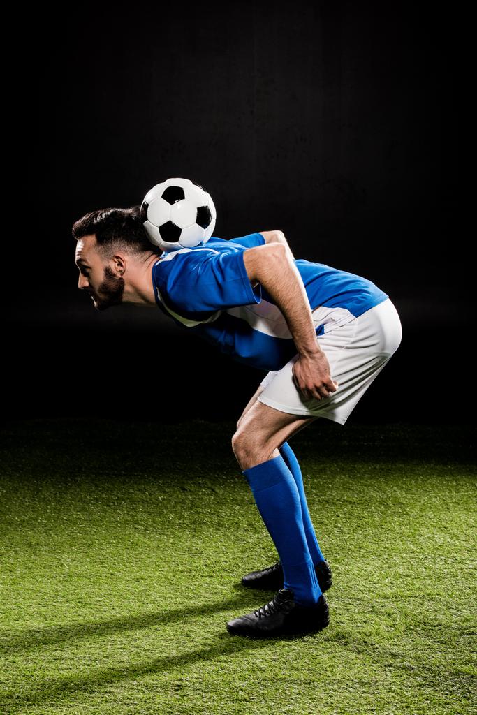 sportsman in uniform training with ball on grass isolated on black - Photo, Image