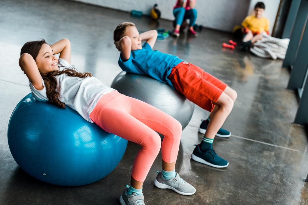 Niños haciendo ejercicios abdominales con pelotas de fitness
 - Foto, Imagen