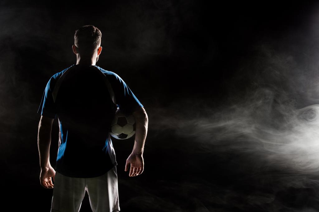 силуэт человека, стоящего в форме с мячом на черном от дыма
   - Фото, изображение