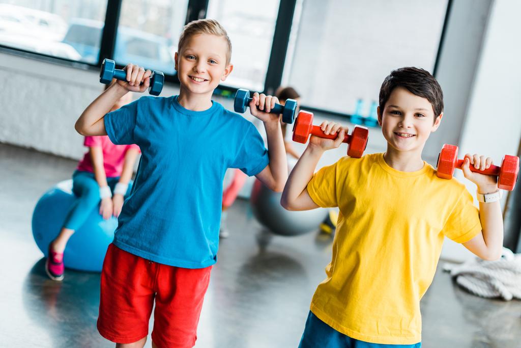 Niños alegres riendo mientras entrenan con pesas
 - Foto, Imagen