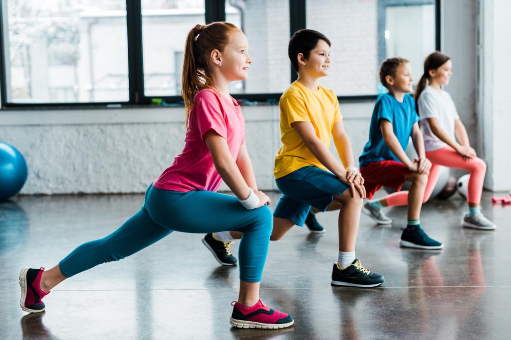 Group of cheerful kids doing stretching in gym - Photo, Image