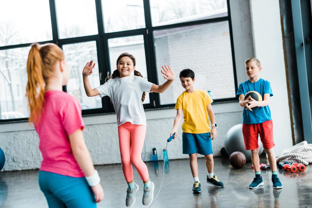 Geïnspireerd kinderen springen met springtouw in sportschool - Foto, afbeelding