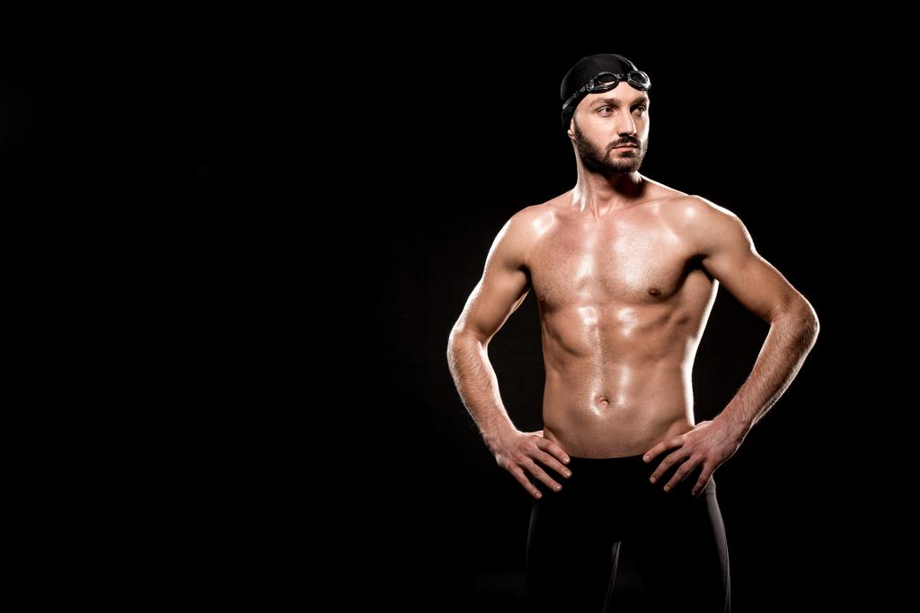 nadador muscular de pé em touca de natação e óculos de natação isolados em preto
 - Foto, Imagem