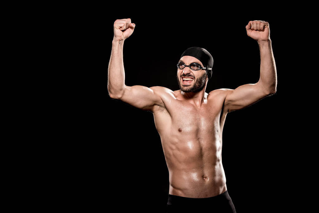 весёлый пловец, стоящий в плавательной шапке и празднующий победу, изолированный на черном
 - Фото, изображение