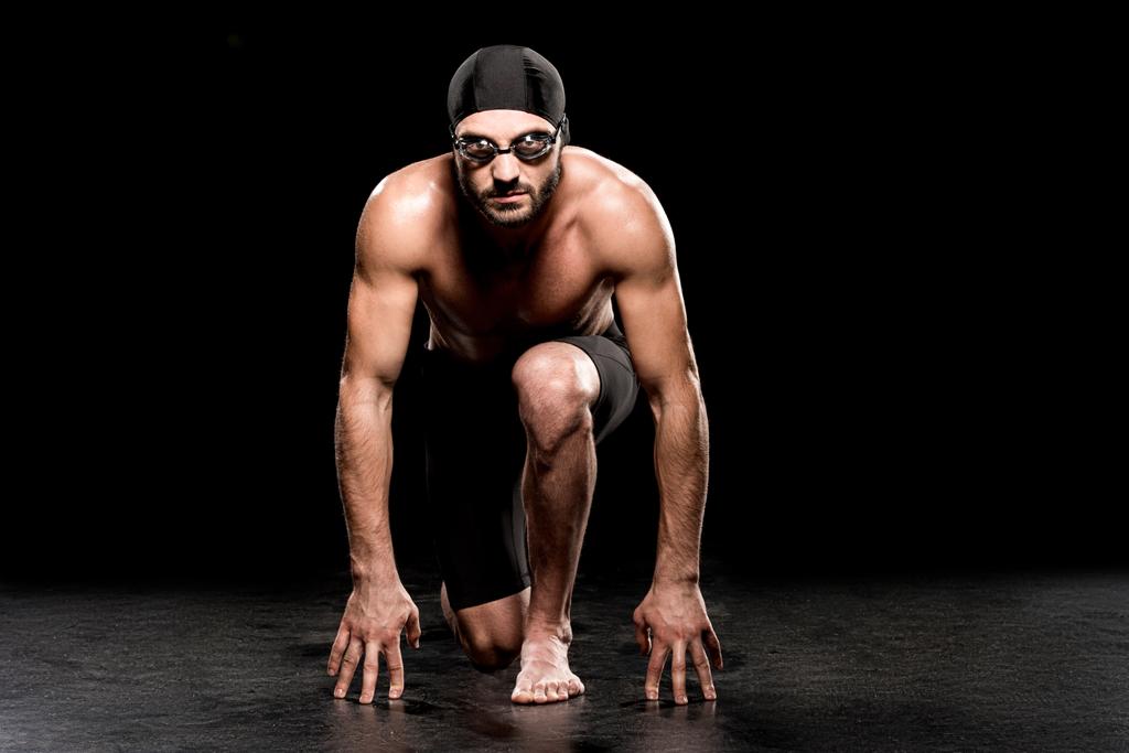 nuotatore atletico in piedi in posizione di partenza su sfondo nero
  - Foto, immagini