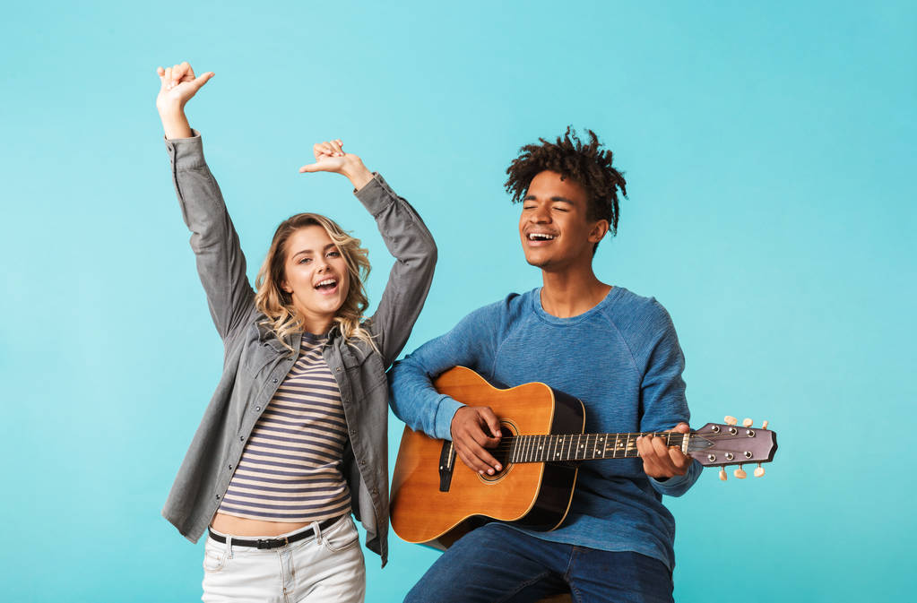 Szczęśliwy multiethninc Młoda para razem, grającego na gitarze na białym tle niebieski - Zdjęcie, obraz