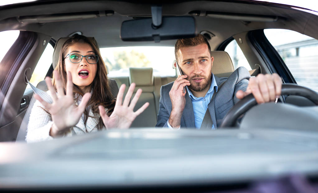 Chica entrando en pánico en el coche como su novio conduce y habla por teléfono en el mismo tiempo
 - Foto, Imagen