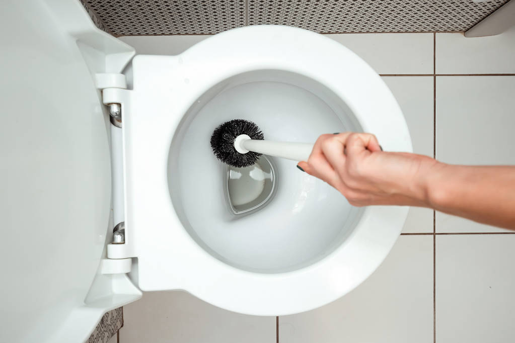 Γκρο πλαν, γυναικείο χέρι νίβει μια βούρτσα τουαλέτας. Η έννοια της καθαριότητας στο σπίτι, υγιεινή, τουαλέτα, μικρόβια. - Φωτογραφία, εικόνα