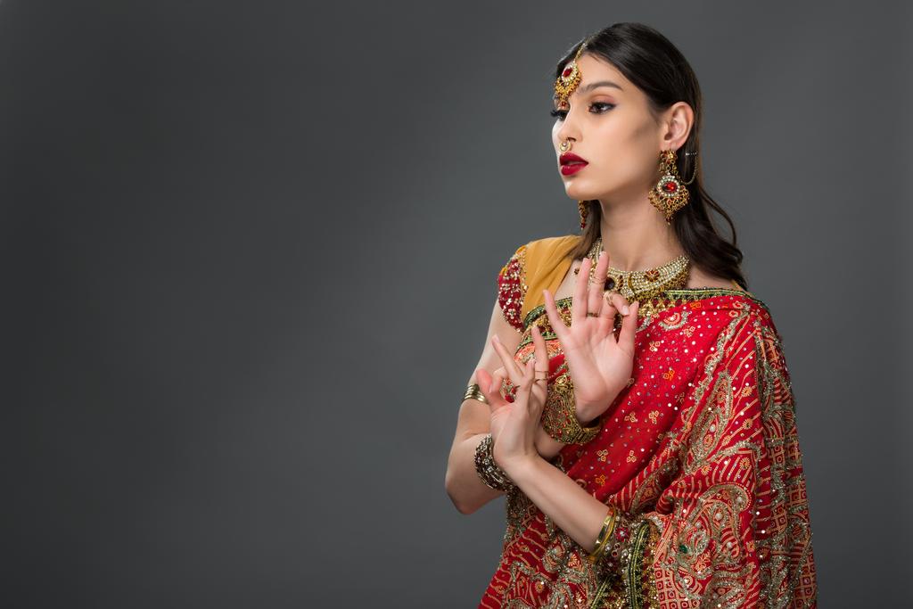 グレーに分離された、伝統的な服を示すギャン ムードラの魅力的なインドの女性  - 写真・画像