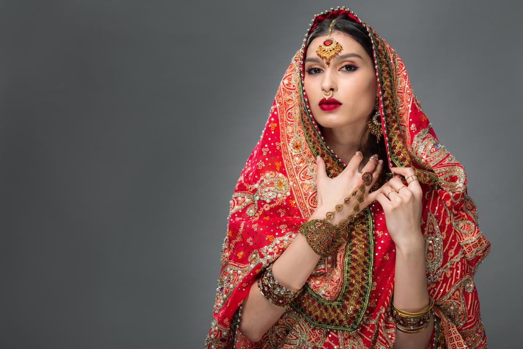 attraktive Indianerin posiert in traditionellem Sari und Accessoires, isoliert auf grau  - Foto, Bild