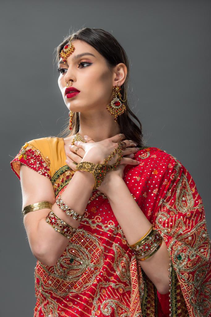 prachtige Indiase vrouw in sari en accessoires, geïsoleerd op grijs  - Foto, afbeelding