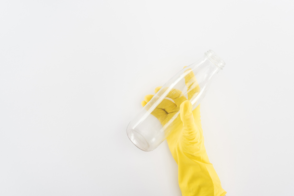 Περικοπεί θεώρηση του ανθρώπου στα κίτρινα λαστιχένια γάντια κρατώντας το άδειο γυάλινο μπουκάλι - Φωτογραφία, εικόνα