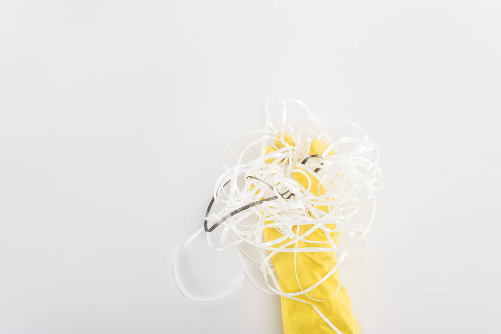 Обрезанный вид человека в жёлтых резиновых перчатках с бумажными полосками на сером фоне
  - Фото, изображение