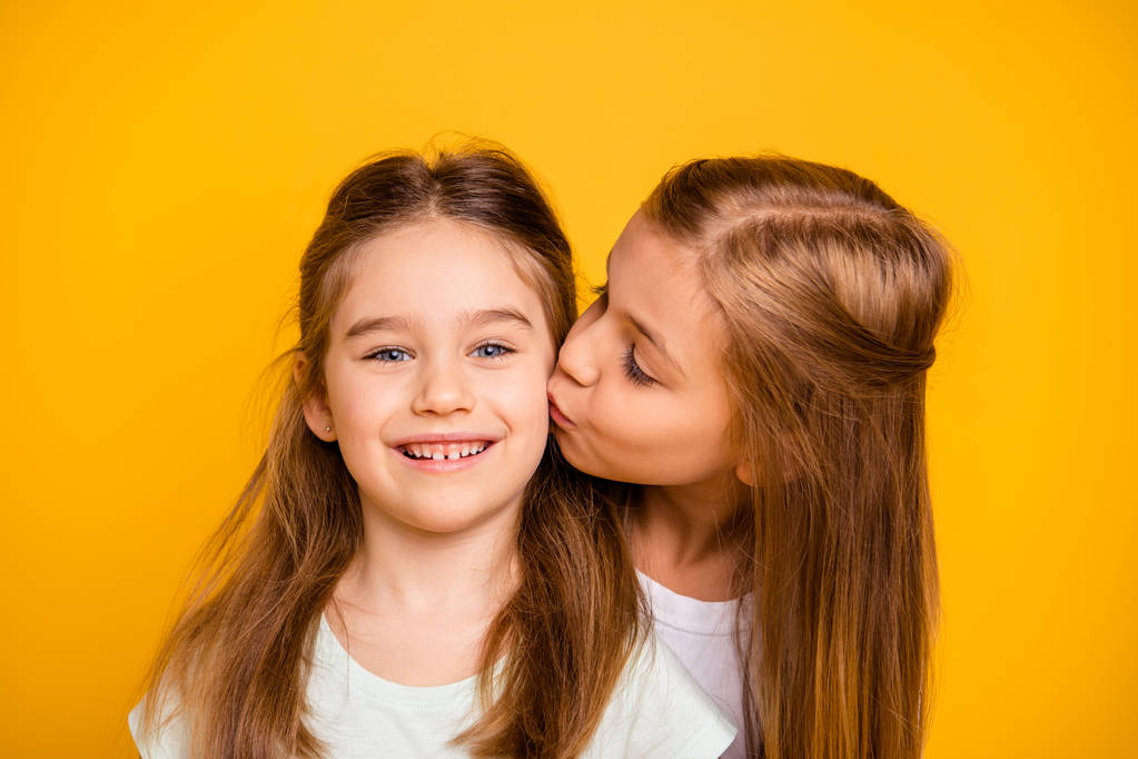 Detail portrét dvou pěkné rozkošný atraktivní krásné sladké veselá veselý pozitivní dívčí dívek baví líbání péče podpora důvěry izolovaný jasný a intenzivní lesk žluté pozadí - Fotografie, Obrázek