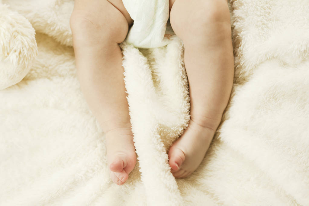 Yeni doğmuş bir bebek bir ekose kemiren küçük nazik sağlıklı bacaklar. Sağlıklı çocuk kavramı - Fotoğraf, Görsel