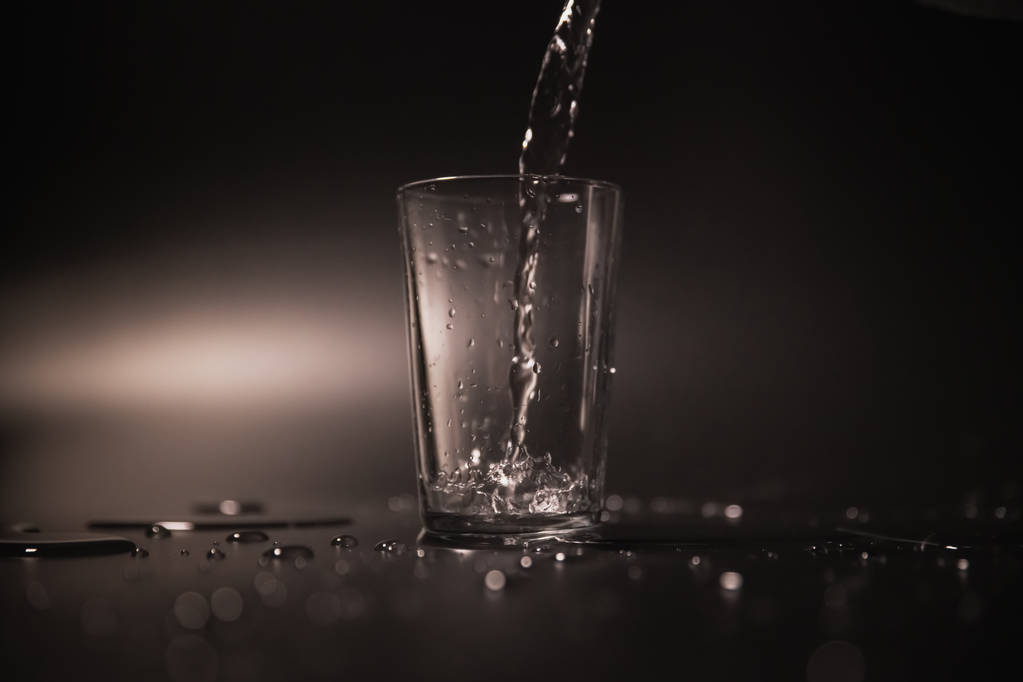 auf schwarzem Hintergrund in einem Glas Wasser gegossen - Foto, Bild