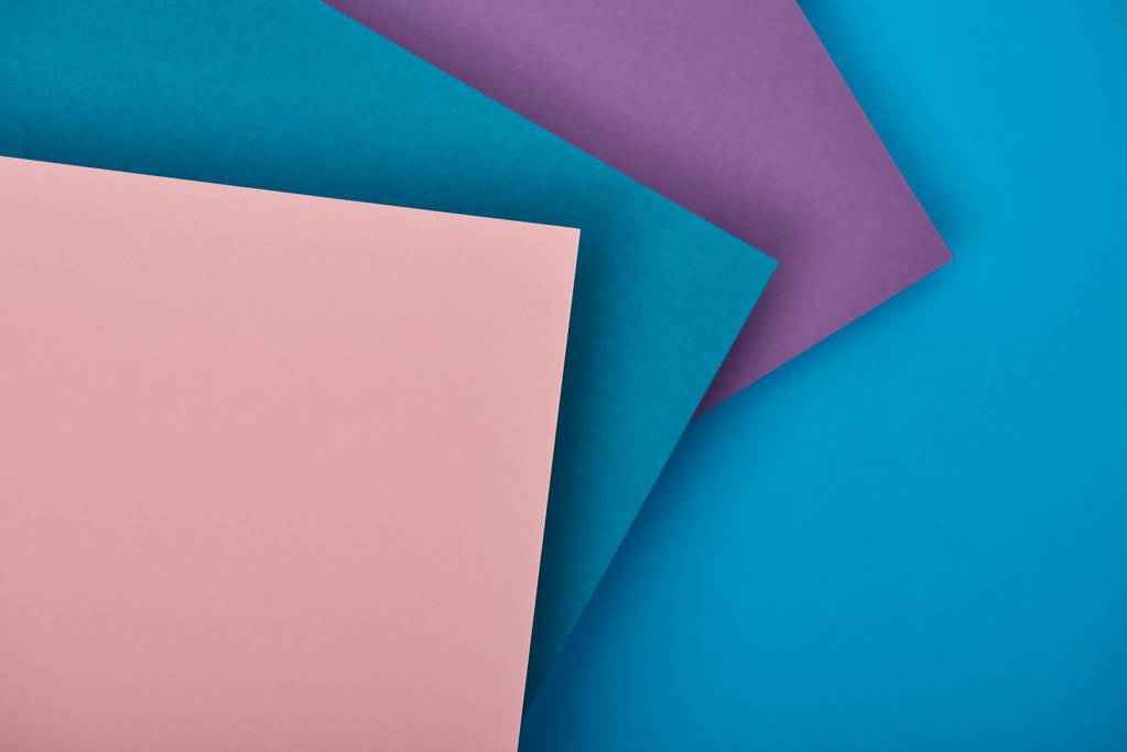 Draufsicht auf blaue, lila und rosa Papierblätter mit Kopierraum - Foto, Bild