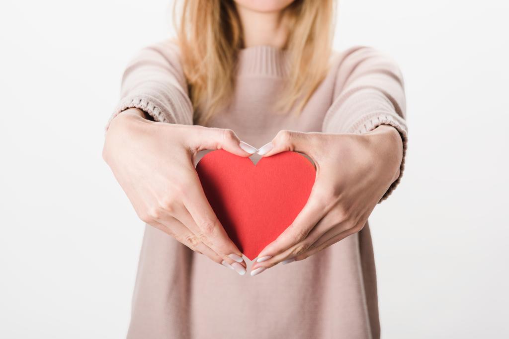 Částečný pohled blondýnka v béžové svetru drží papír srdce na bílém podkladu - Fotografie, Obrázek