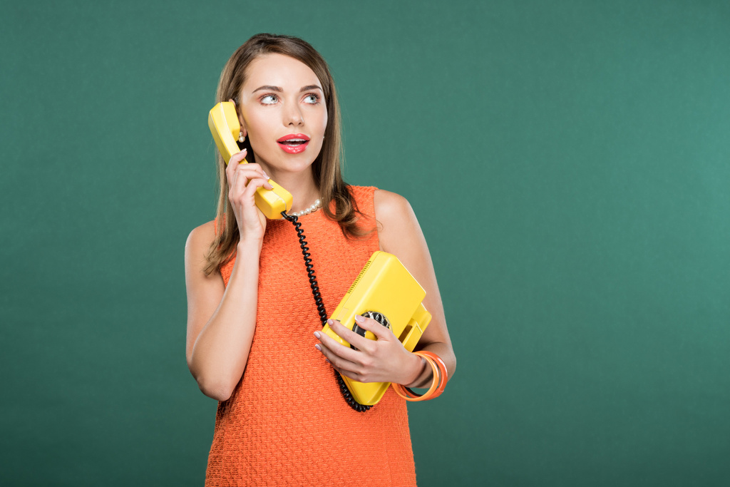 beautiful stylish woman talking on retro telephone isolated on green with copy space - Photo, Image