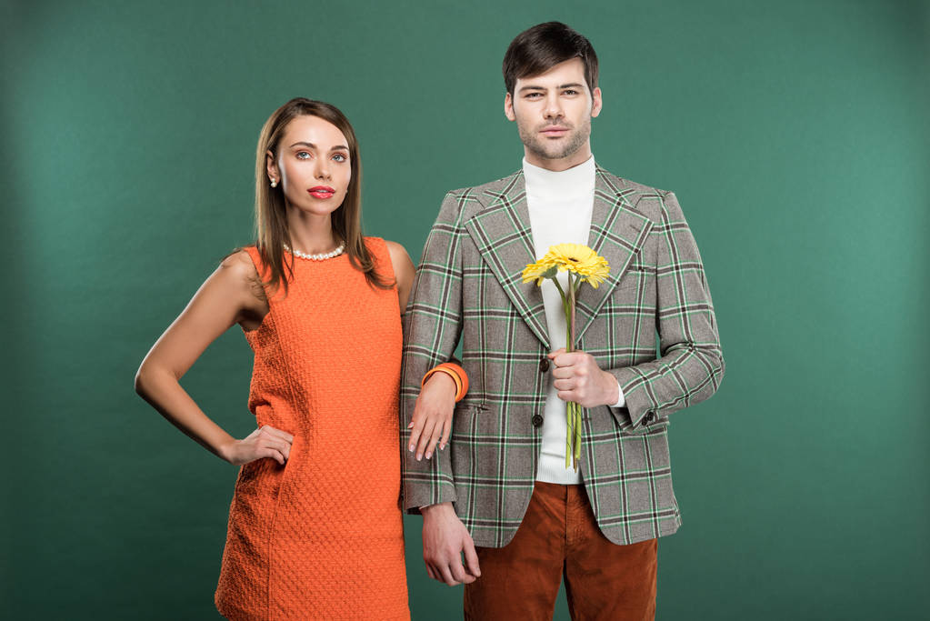 красивая пара в винтажной одежде с цветами глядя на камеру изолированы на зеленый
 - Фото, изображение