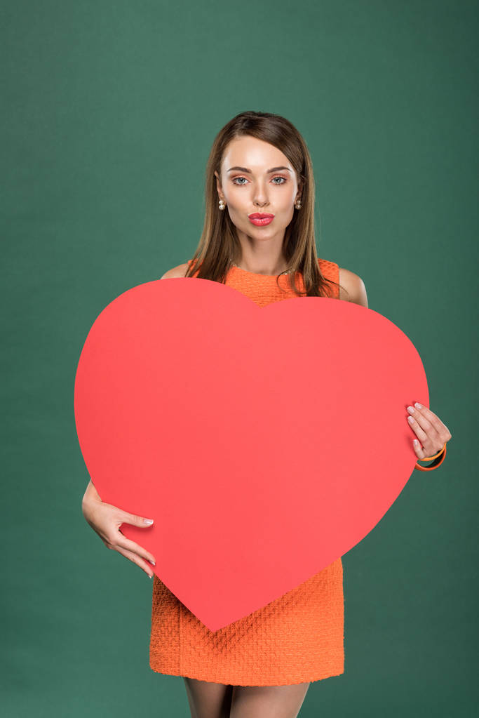 beautiful woman holding heart shaped paper card with copy space isolated on green - Photo, Image