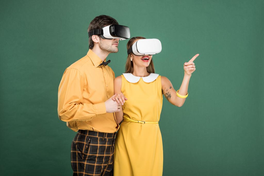 aufgeregtes Paar in Vintage-Kleidung und Virtual-Reality-Headset isoliert auf grün - Foto, Bild