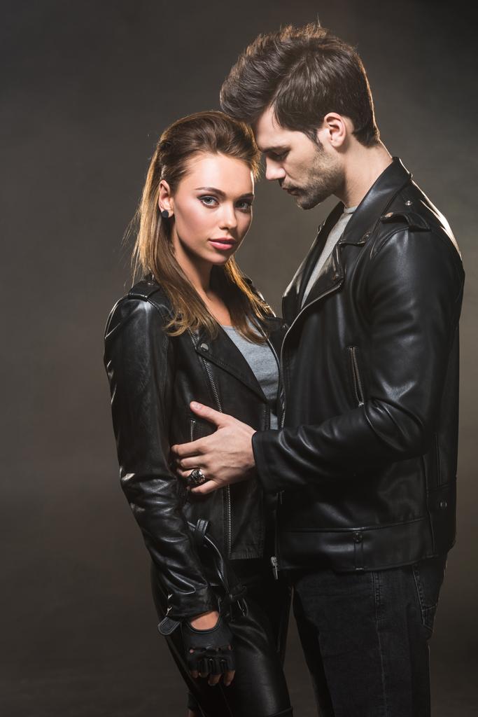 beautiful couple in leather jackets embracing on dark background - Photo, Image
