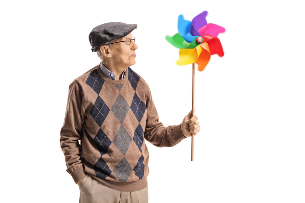 Hombre mayor sosteniendo un molinete giratorio y mirándolo aislado sobre fondo blanco
 - Foto, Imagen