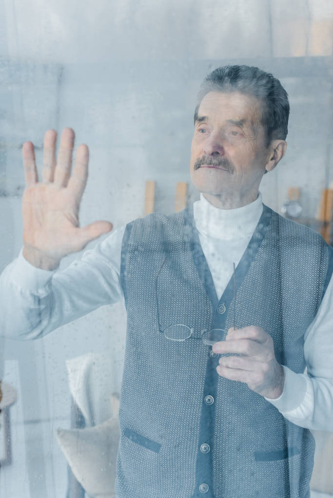 расстроен старший мужчина размахивая рукой, стоя у окна
  - Фото, изображение