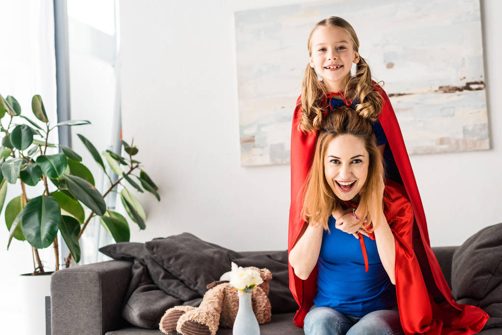 Lächelnde Mutter und Kind in roten Mänteln blicken in die Kamera - Foto, Bild