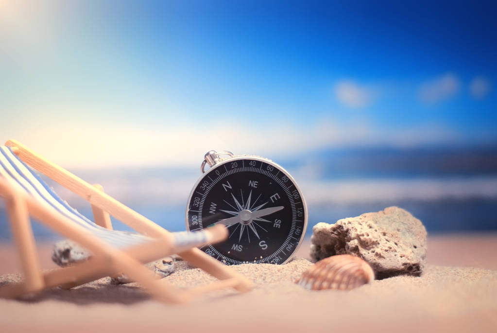 Время путешествовать. Идея для туризма с компасом и шезлонгом на песке с кораллами на фоне моря
 - Фото, изображение