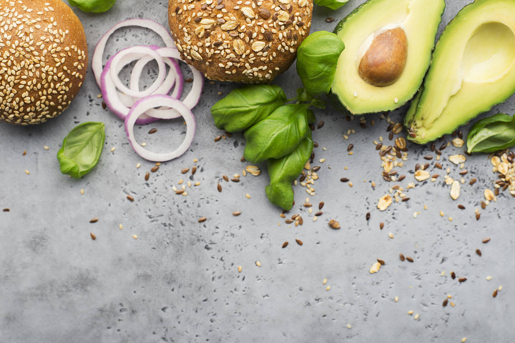 Ingrediënten voor het maken van gezonde vegetarische avocado hamburger met basilicum, rode ui, avocado op granen broodjes. Lichte achtergrond grijs. Bovenaanzicht, ruimte. - Foto, afbeelding