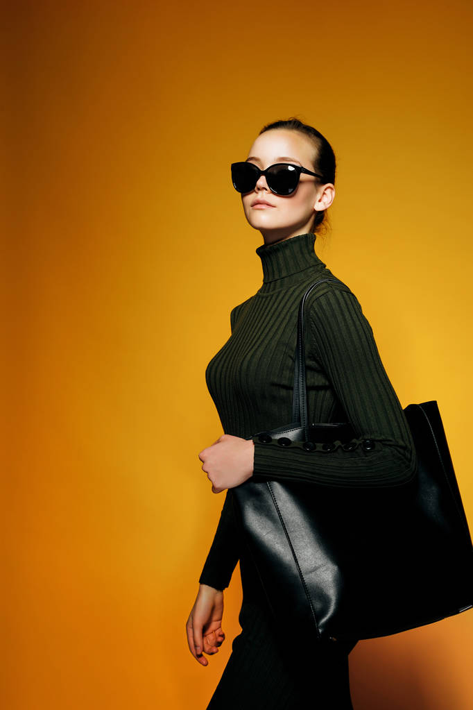 Concept de vente Black Friday. Shopping femme tenant sac en cuir noir isolé sur fond jaune
 - Photo, image