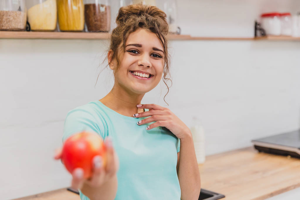 Mujer joven feliz comiendo manzana en la cocina. Dieta. Concepto de dieta. Alimento saludable
. - Foto, imagen
