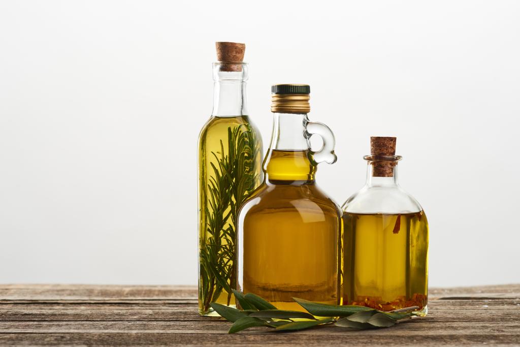 frascos de aceite de oliva aromatizados con romero y especias aisladas en gris
  - Foto, imagen