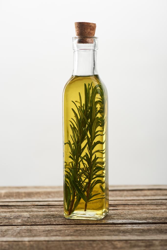 Flasche aromatisiertes Öl mit Rosmarinzweigen auf Holzoberfläche - Foto, Bild