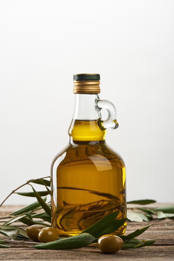 bottle of oil with olive tree leaves and olives isolated on grey  - Photo, Image