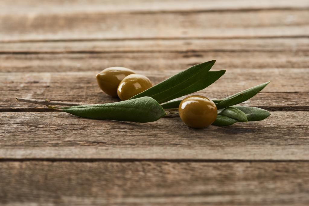 rama de olivo y aceitunas verdes en la superficie de madera
 - Foto, Imagen