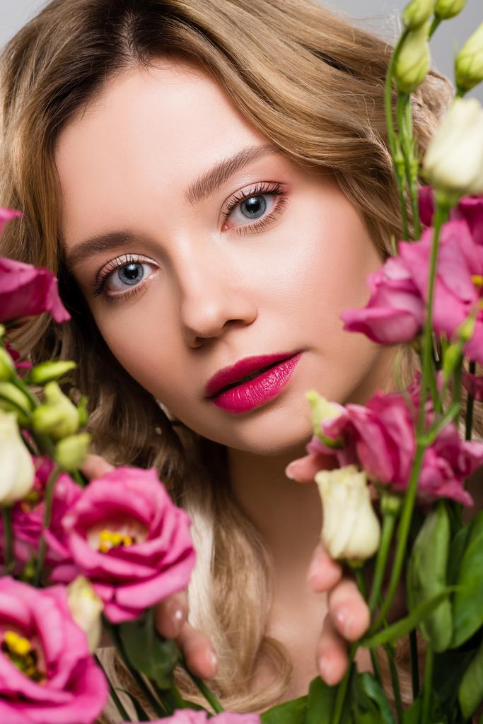 Nahaufnahme des Frühlings junge Frau schaut durch Eustoma-Blumen - Foto, Bild