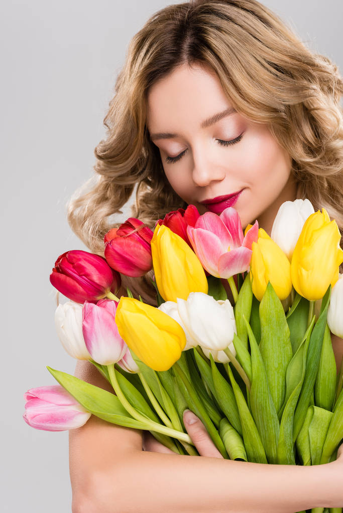 voorjaar van jonge aantrekkelijke vrouw met gesloten ogen houden boeket van kleurrijke tulpen geïsoleerd op grijs  - Foto, afbeelding