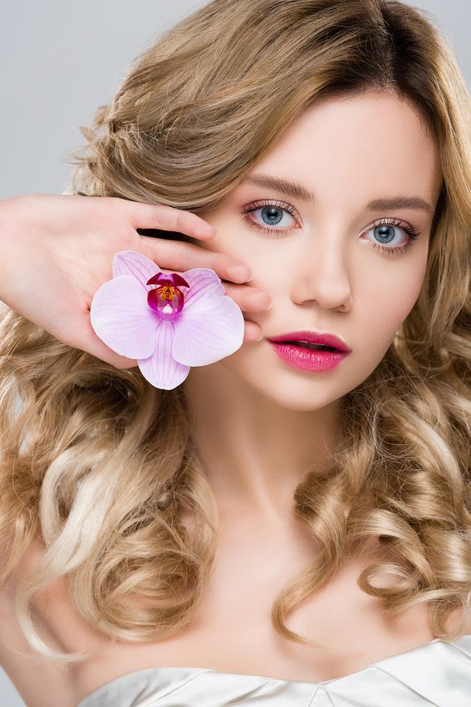 young blonde attractive woman holding purple orchid in palm isolated on grey - Photo, Image
