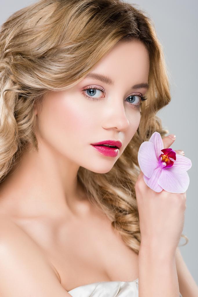 jovem elegante bela mulher segurando orquídea roxa na mão isolado em cinza
 - Foto, Imagem