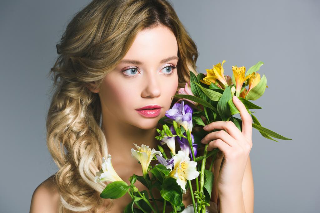 attractive blonde young woman holding flowers in hand - Photo, Image