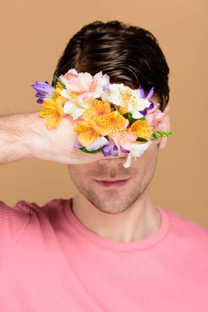 człowiek pod ręką zasłania twarzy z kwiatami na białym tle na beżowy - Zdjęcie, obraz