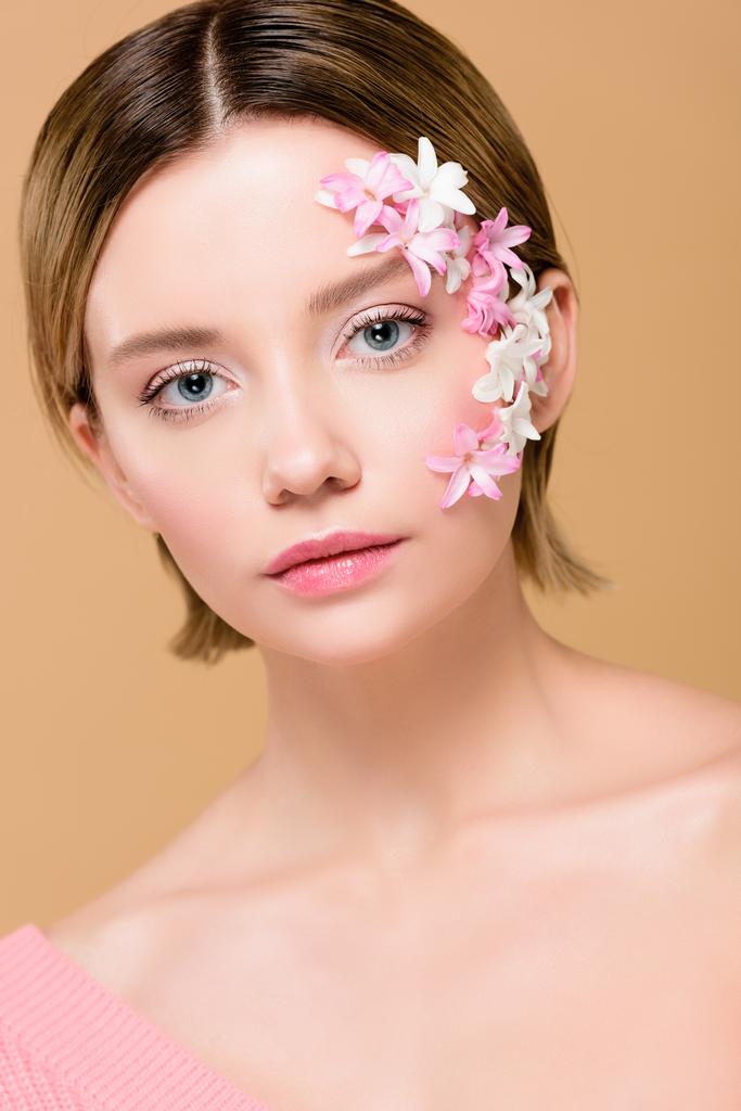 beautiful girl with flowers on face looking at camera isolated on beige - Photo, Image