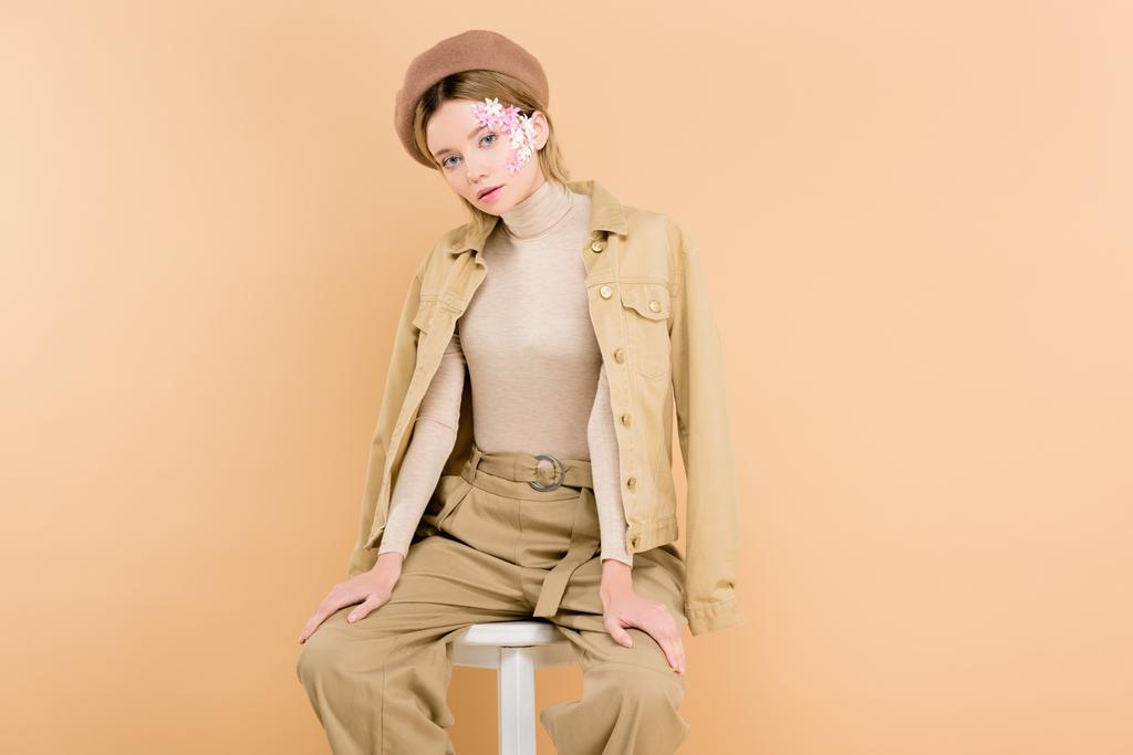 trendy woman in beret sitting on chair isolated on beige  - Photo, Image