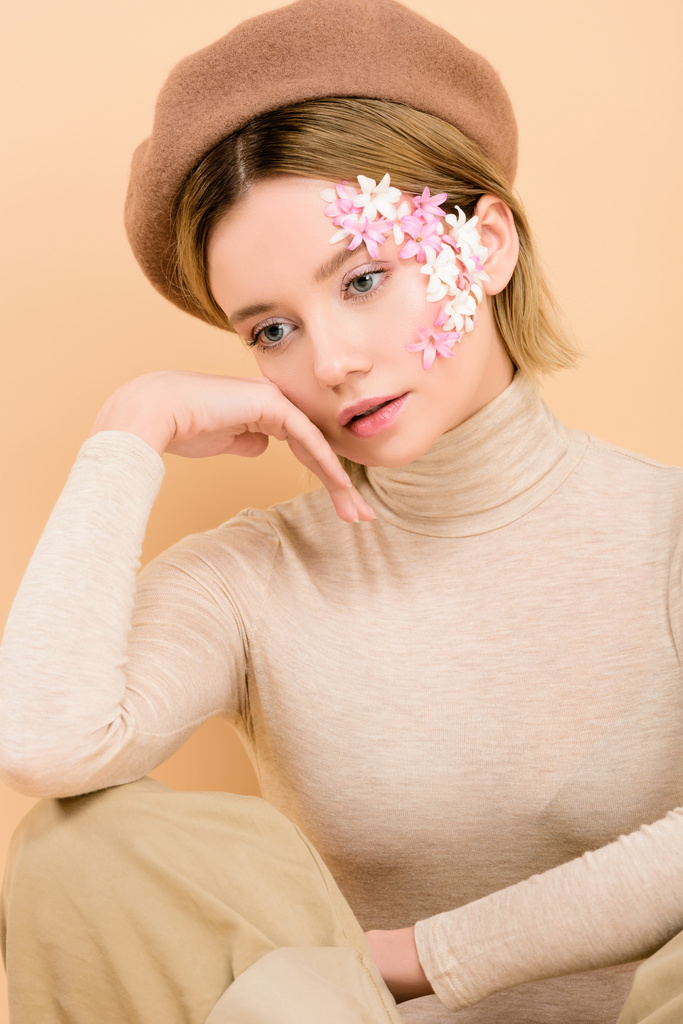 attraente ragazza in berretto toccare faccia isolato su beige
  - Foto, immagini